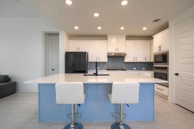 a kitchen with granite countertop a sink and white cabinets