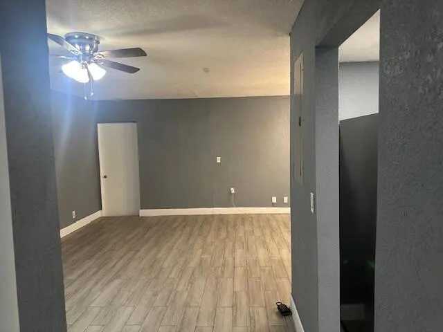 an empty room with wooden floor chandelier fan and windows