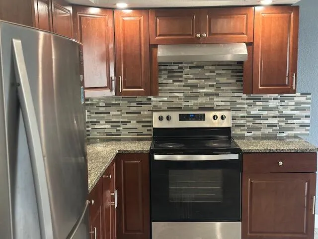 a kitchen with granite countertop a stove and a refrigerator