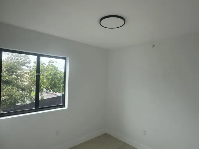 a view of a hallway with wooden floor and a bathroom