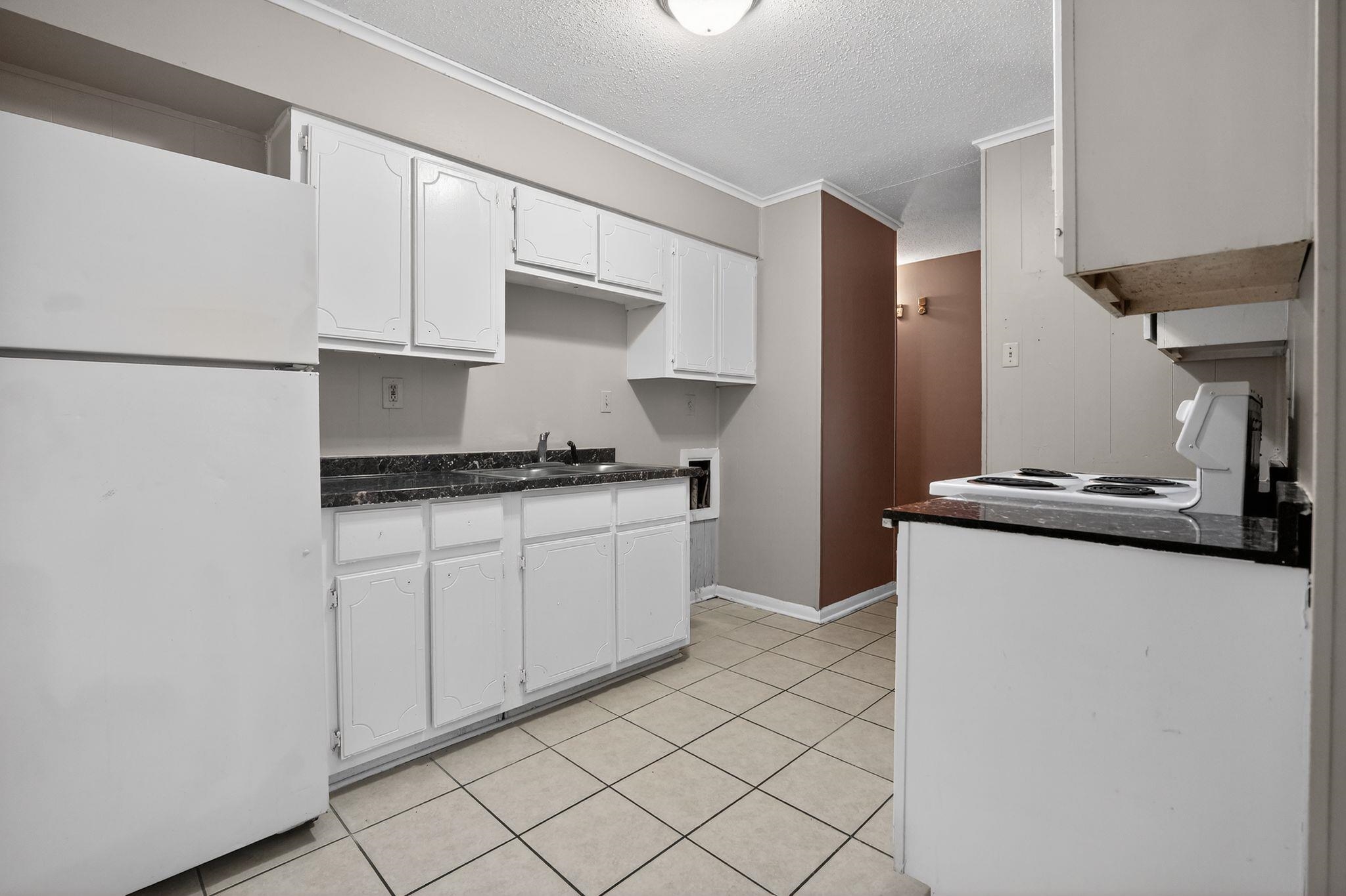 4566 Weaver Road Memphis, TN 38109 - Photo 11 of 32 a kitchen with granite countertop white cabinets and stainless steel appliances