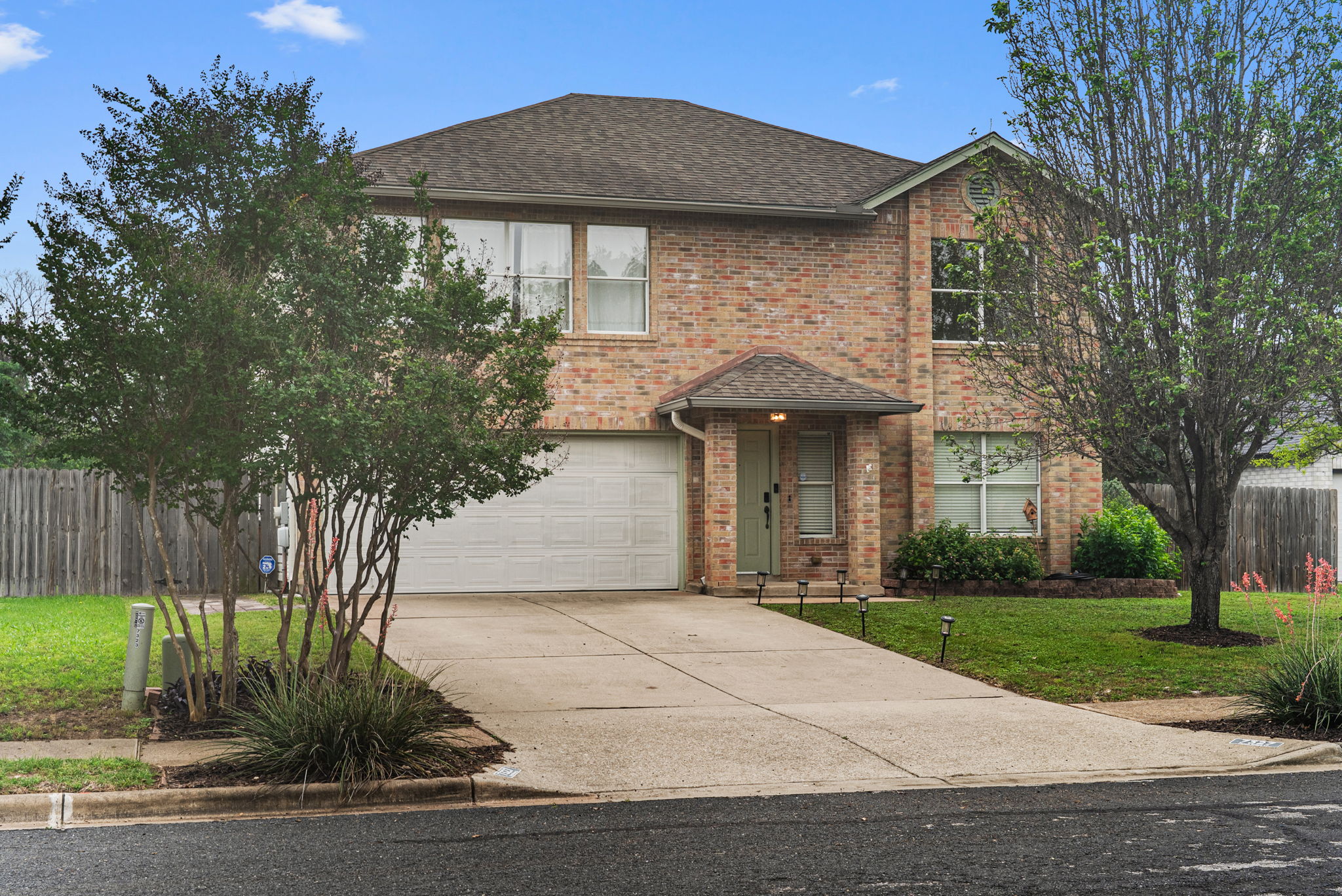 Two-story brick facade residence featuring a covered entry, an attached garage, and a concrete driveway