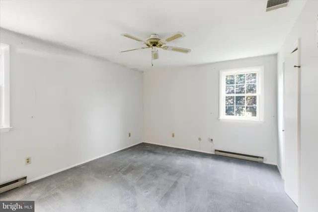 an empty room with a window and a ceiling fan