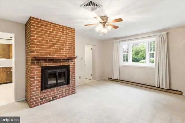 an empty room with windows fireplace and fan