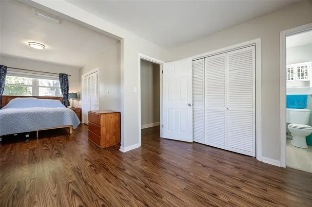 a spacious bedroom with a bed and wooden floor