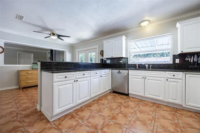 a kitchen with granite countertop a sink window and cabinets