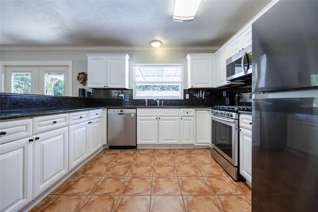 a kitchen with granite countertop a sink a counter top space appliances and cabinets