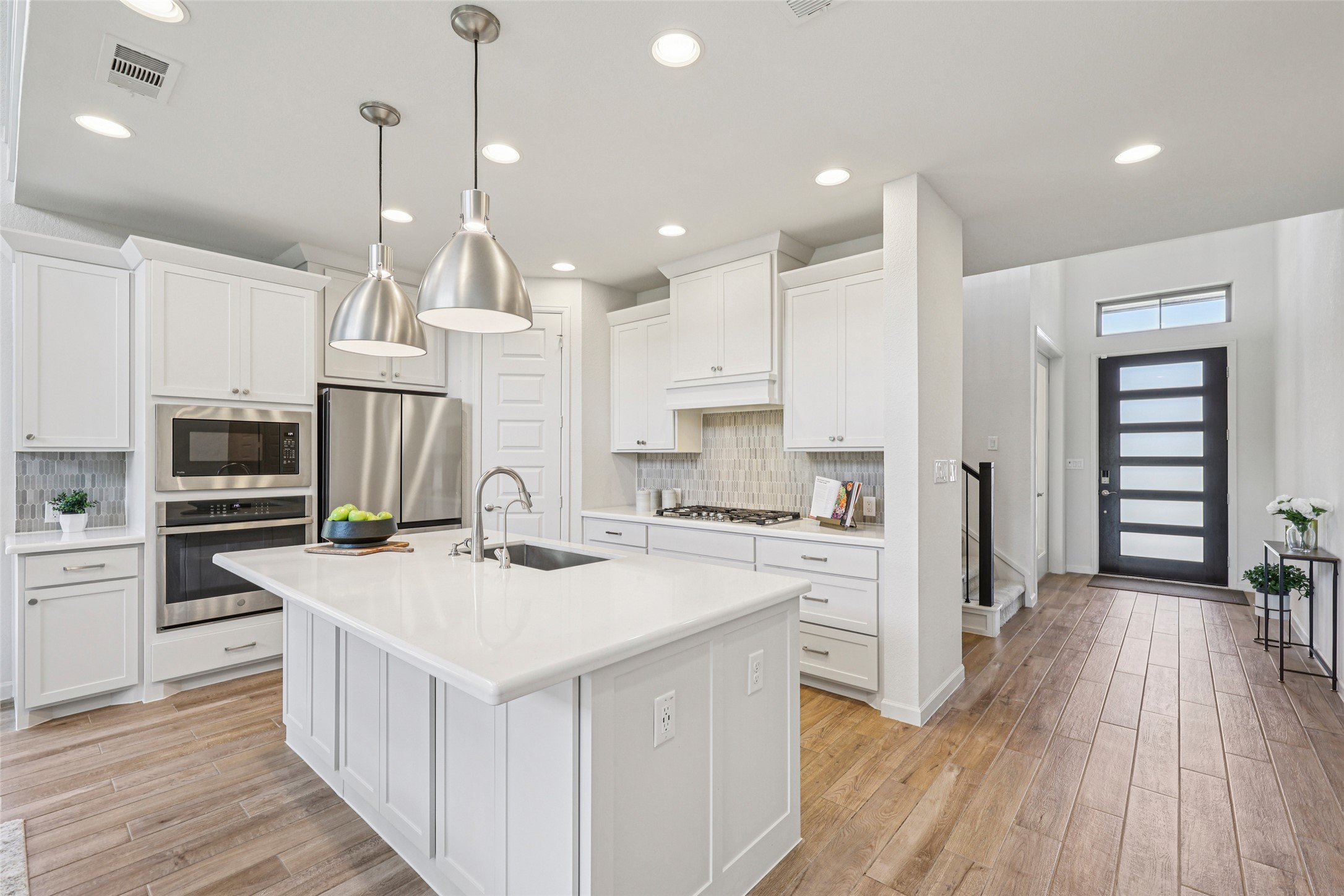 1140 Bryson Rdg Trail Leander, TX 78641 - Photo 5 of 39 The kitchen features white cabinetry, stainless steel appliances, a white island with an integrated sink, and recessed lighting