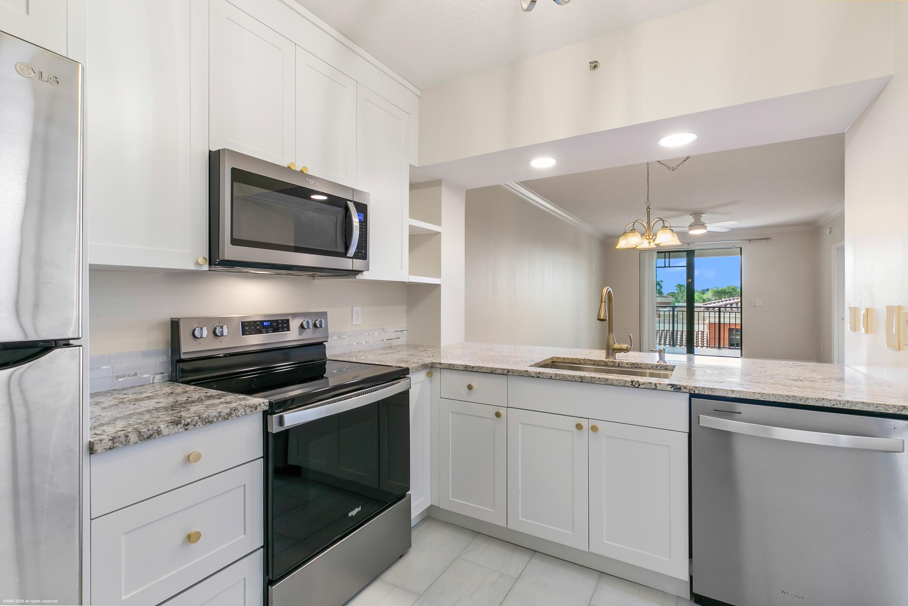 a kitchen with granite countertop white cabinets stainless steel appliances and a sink