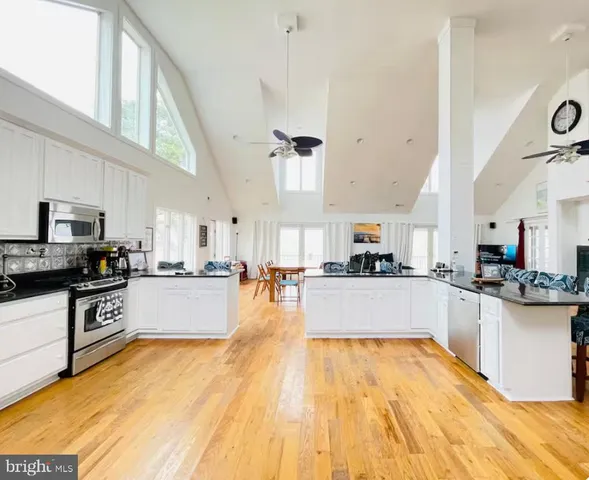 a living room with couches and kitchen view with wooden floor
