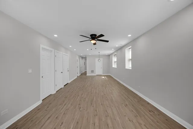 a view of empty room with wooden floor and ceiling fan