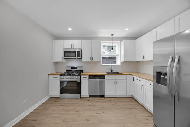 a kitchen with stainless steel appliances granite countertop a stove top oven a sink and a refrigerator