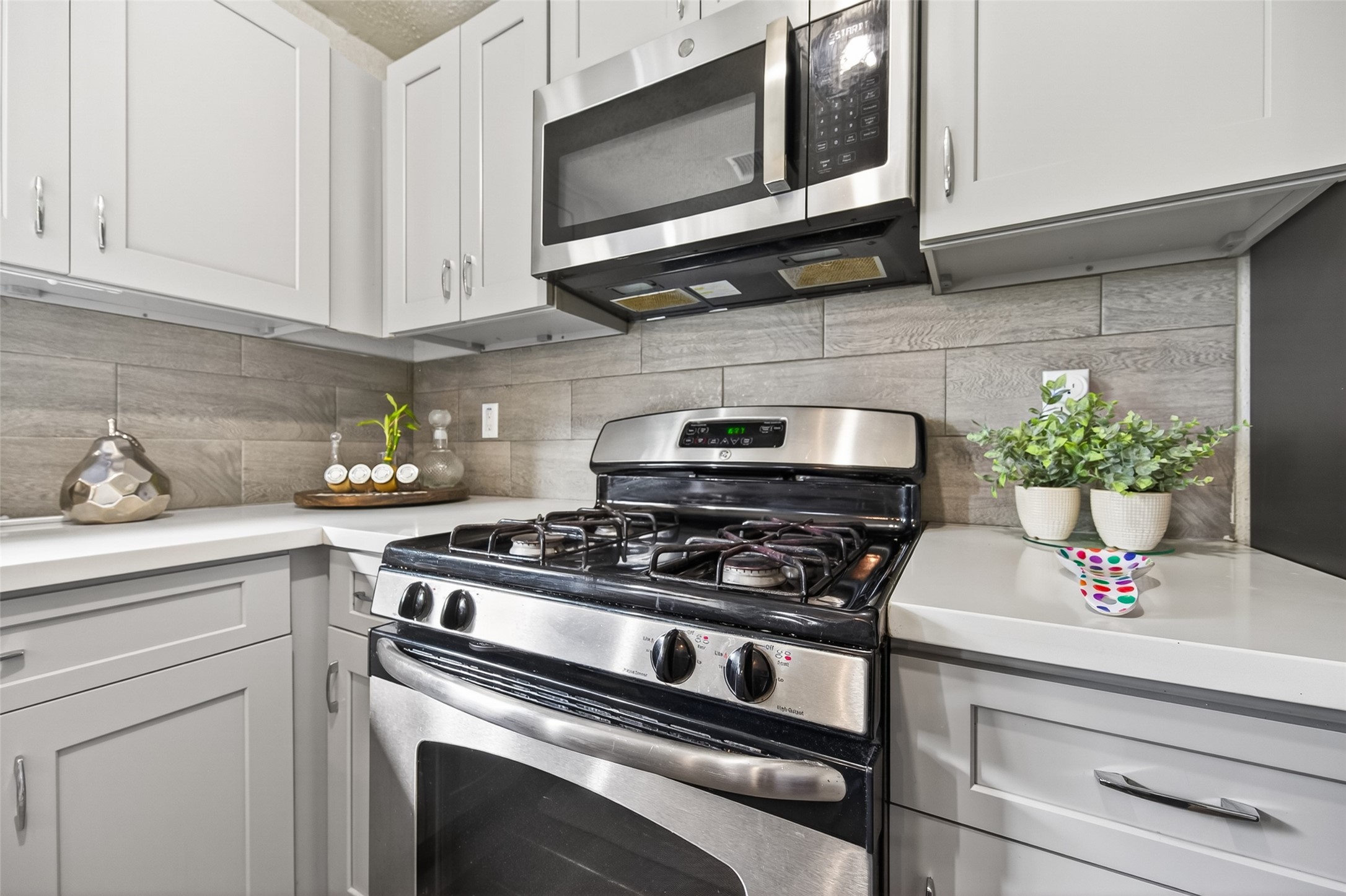 18446 North Willow Bluff Road Katy, TX 77449 - Photo 15 of 33 Modern kitchen with sleek stainless steel appliances, white cabinetry, and a clean, tiled backsplash. Ideal for cooking enthusiasts.