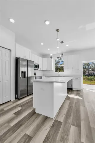 a kitchen with stainless steel appliances kitchen island a refrigerator sink and cabinets