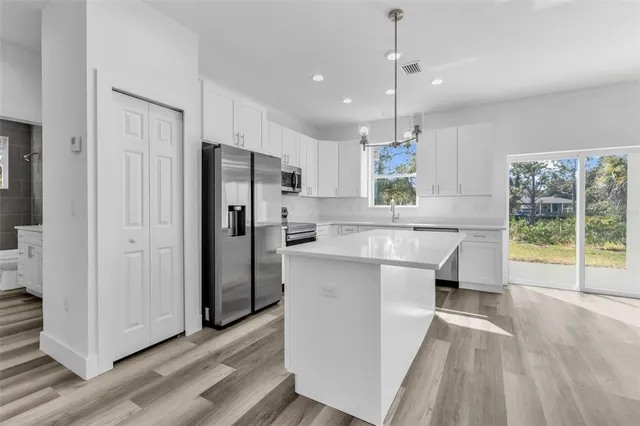 a kitchen with kitchen island a counter top space a sink a refrigerator and a wooden floor