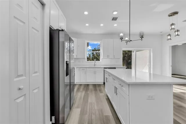 a large kitchen with a large counter top a sink and stainless steel appliances