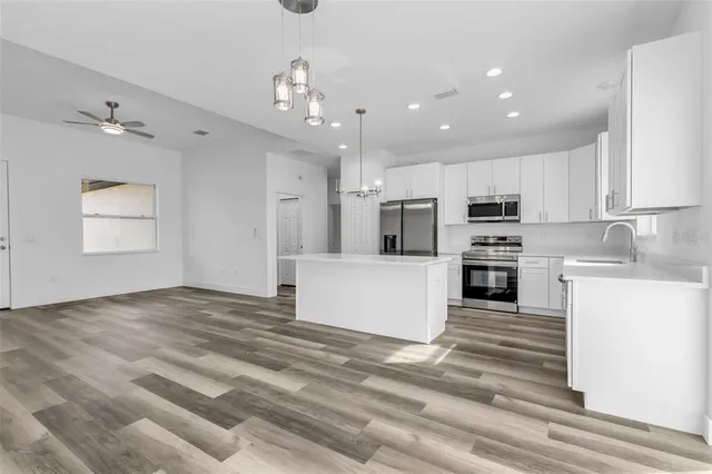 a large kitchen with kitchen island a stove a refrigerator a sink dishwasher and a stove with wooden floor