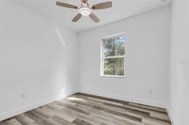 an empty room with windows and fan