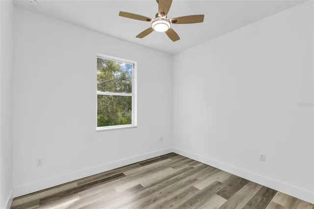 an empty room with a window and a fan