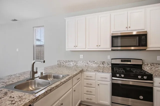 a kitchen with granite countertop white cabinets and stainless steel appliances