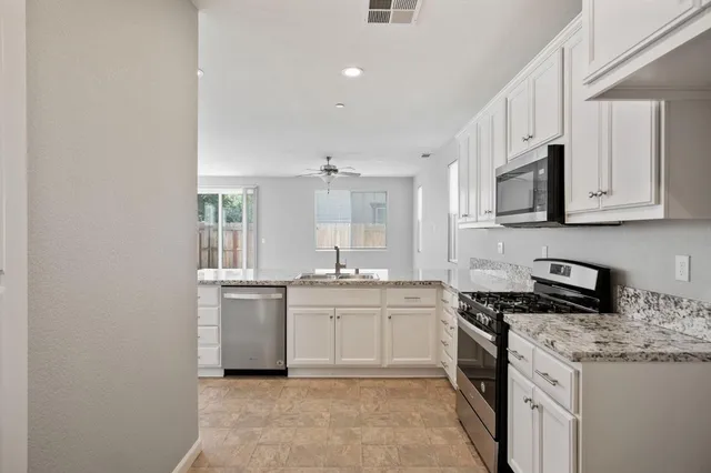 a kitchen with stainless steel appliances granite countertop a stove a sink and a microwave