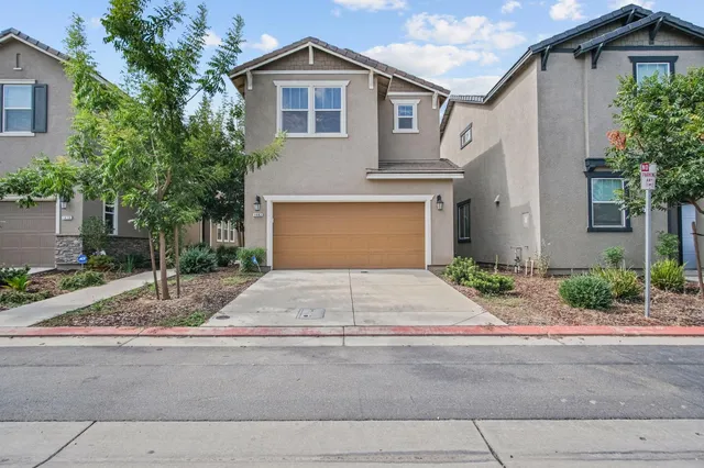 a front view of a house with garage and plants