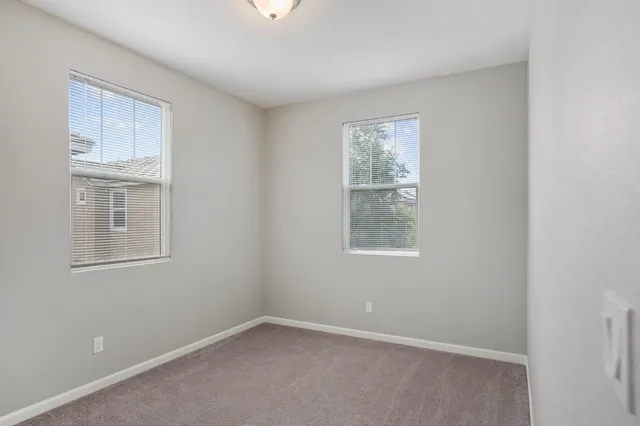 an empty room with windows and ceiling fan