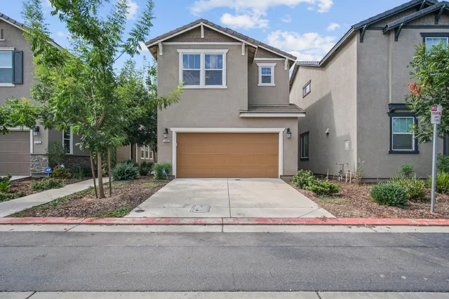 a front view of a house with garage and plants