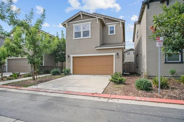 a front view of a house with garage and plants
