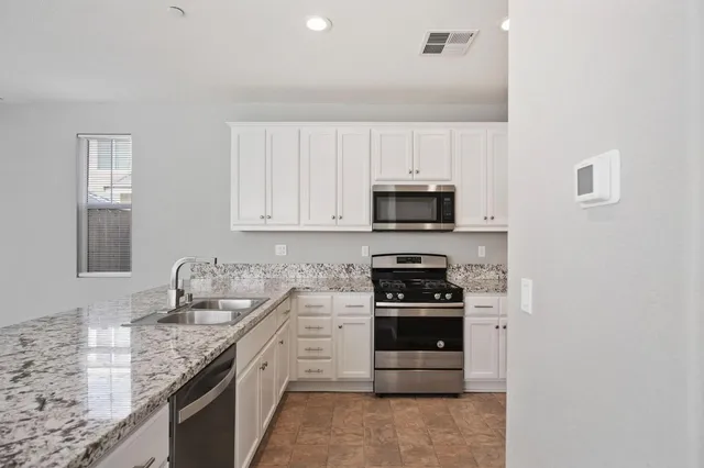 a kitchen with granite countertop a sink and stainless steel appliances