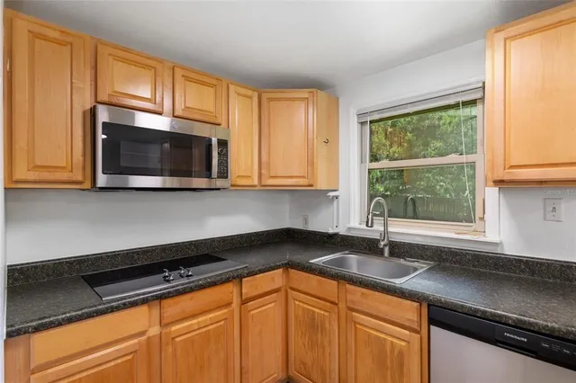 a kitchen with granite countertop a sink a microwave cabinets and window