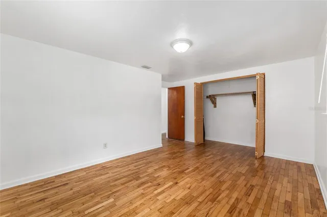 a view of an empty room with wooden floor and closet