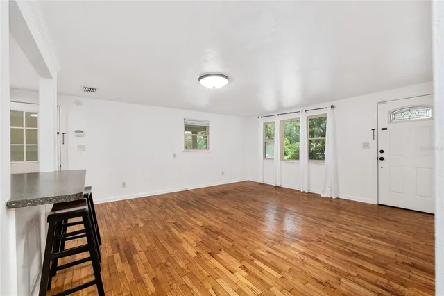 a view of an empty room with wooden floor and a window
