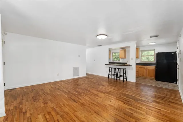 a view of an empty room with window and wooden floor