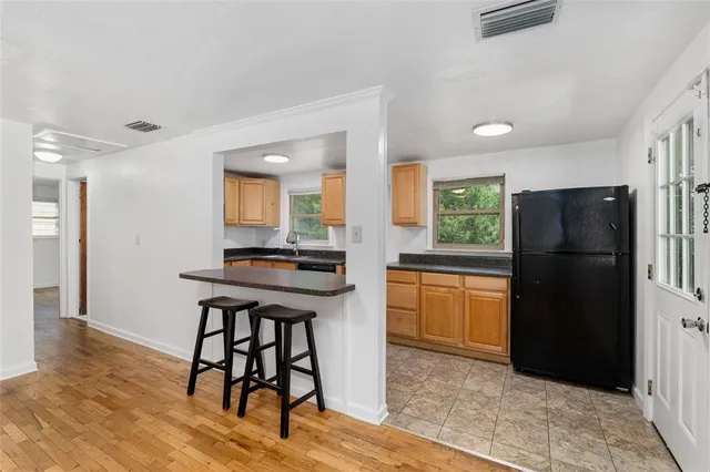 a kitchen with a refrigerator a stove and a dining table with wooden floor