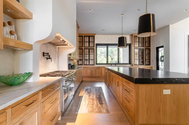 a view of a kitchen with stainless steel appliances granite countertop a sink and a stove