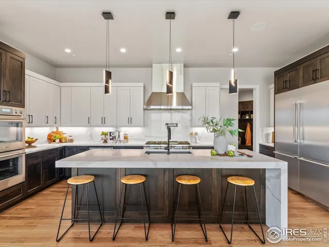 a kitchen with stainless steel appliances granite countertop a stove a sink a refrigerator a center island with a dining table and chairs