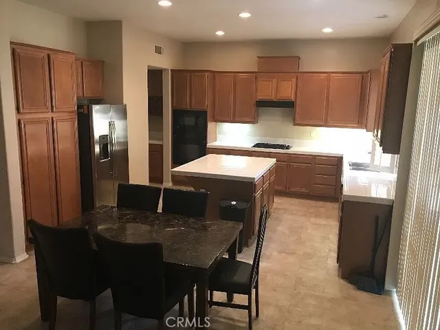 a kitchen with stainless steel appliances granite countertop a stove a refrigerator a sink a dining table and chairs