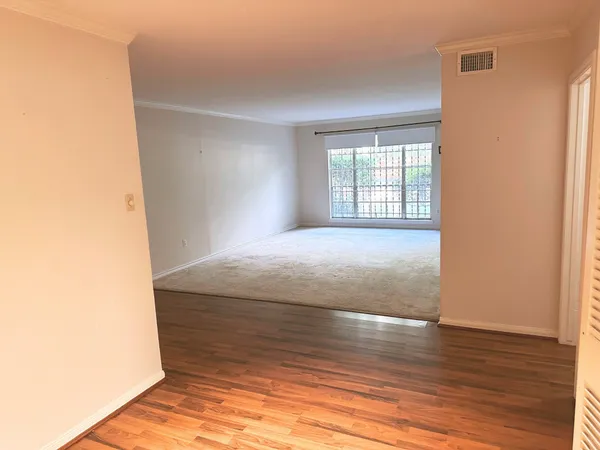 a view of a hallway with wooden floor and a bathroom