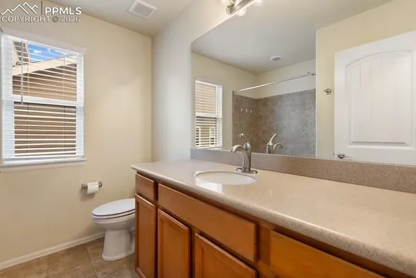 a bathroom with a granite countertop sink toilet and mirror