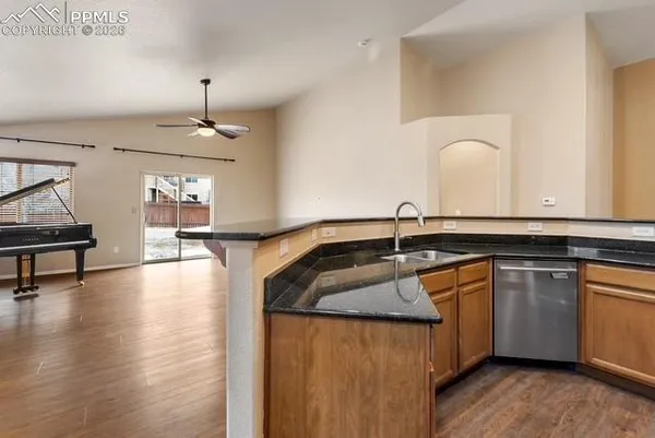 a kitchen with stainless steel appliances granite countertop a sink a stove and a wooden floors