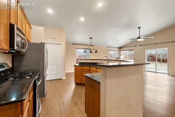 a kitchen with kitchen island stainless steel appliances a sink a stove cabinets and wooden floor