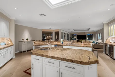 a view of living room kitchen with granite countertop stainless steel appliances and sink