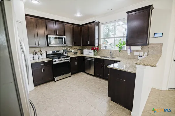 a kitchen with stainless steel appliances granite countertop a sink stove and refrigerator