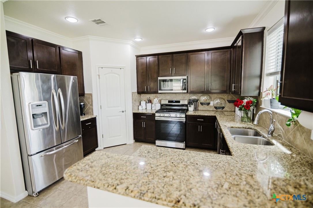 201 Boulder Ridge Drive Cuero, TX 77954 - Photo 9 of 37 a kitchen with granite countertop a refrigerator stove and sink