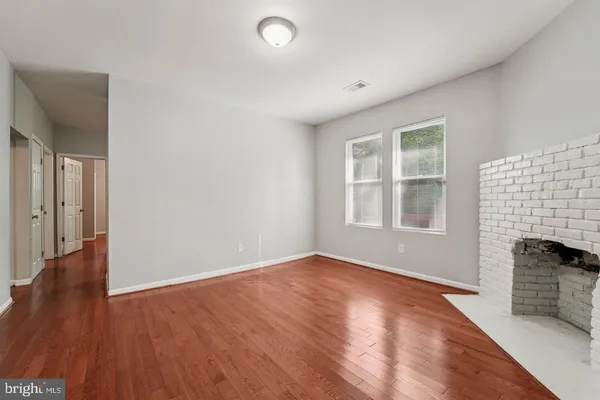 an empty room with wooden floor and fireplace