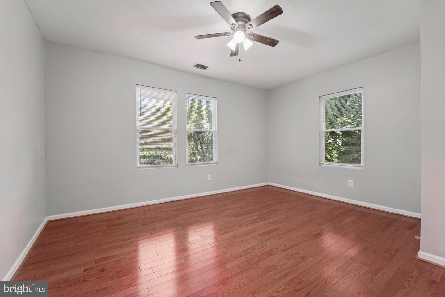 4511 Prospect Circle Baltimore, MD 21216 - Photo 13 of 25 an empty room with wooden floor chandelier fan and windows