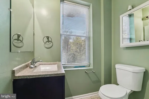 a bathroom with a granite countertop toilet sink and mirror