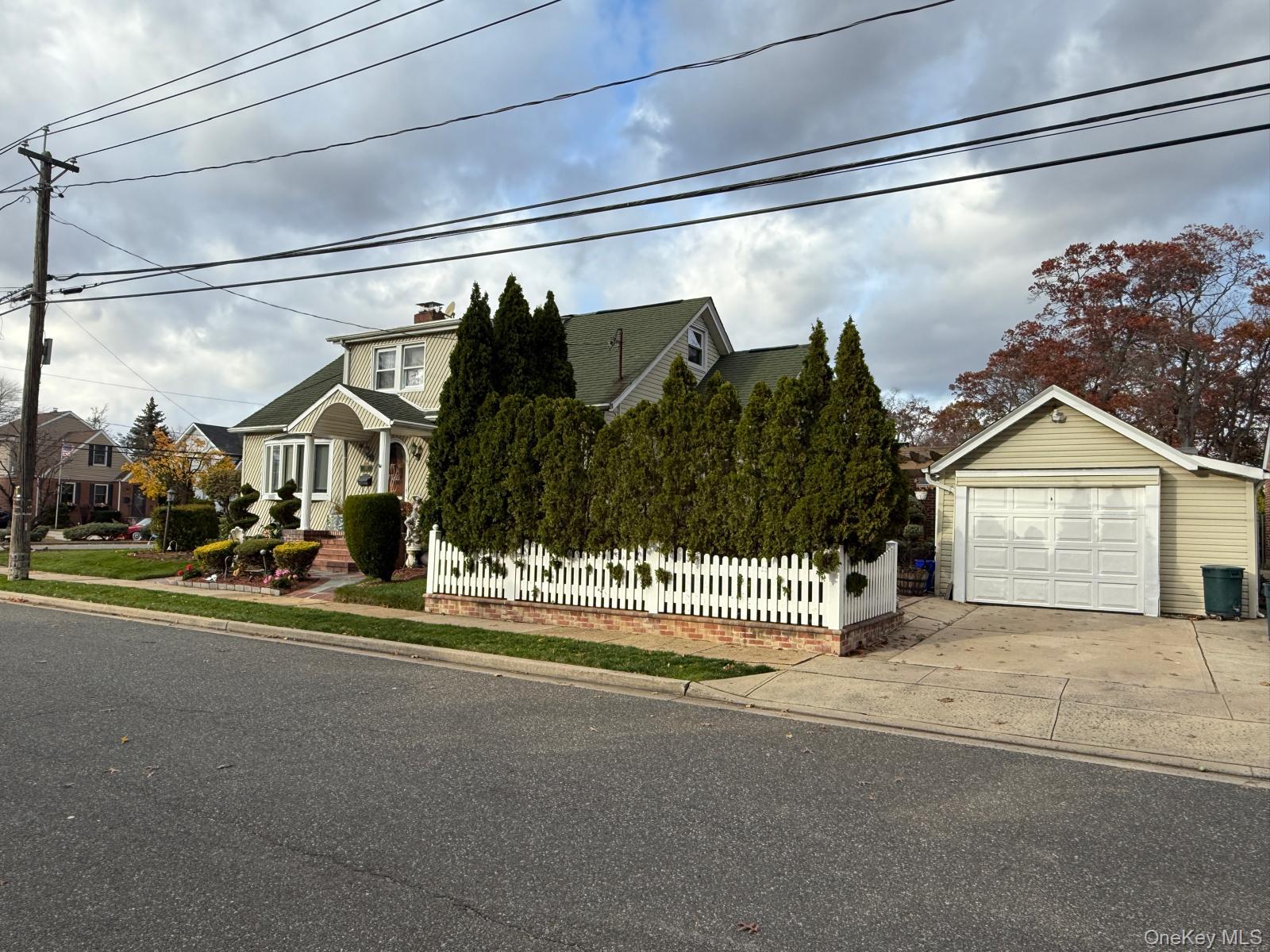 183 North Cottage Street Valley Stream, NY 11580 - Photo 1 of 16 View of front of property with a fenced front yard, concrete driveway, a chimney, and a detached garage