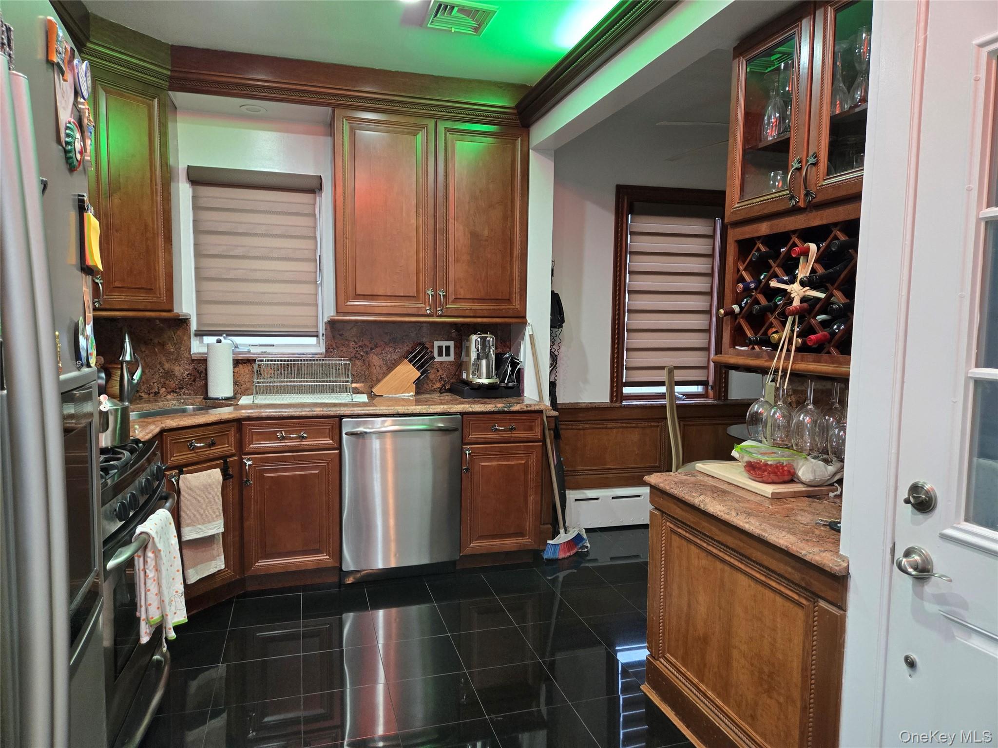 183 North Cottage Street Valley Stream, NY 11580 - Photo 6 of 16 Kitchen featuring appliances with stainless steel finishes, light stone countertops, backsplash, glass insert cabinets, and brown cabinetry